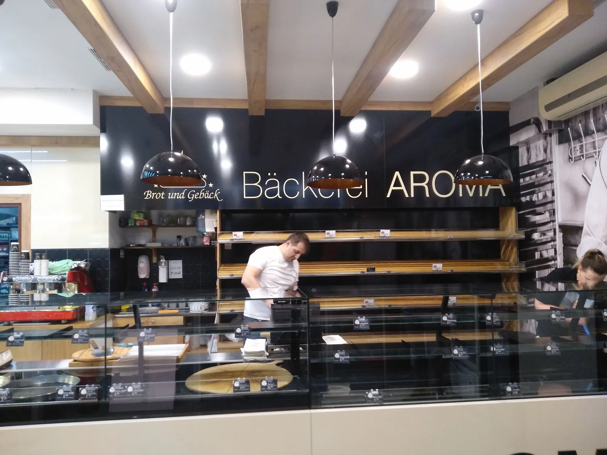 Verkaufsraum der Bäckerei Aroma mit Schriftzug, Holzbalken und Vitrine